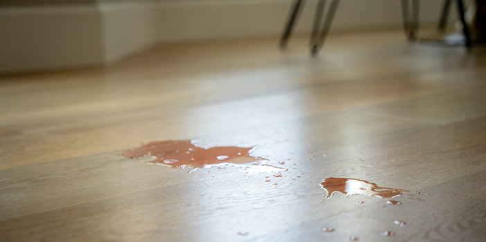 Liquid spill beading on the surface of waterproof light wood-look plank flooring