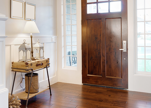 Rich brown hardwood flooring in an entryway foyer with a console table and wood front door