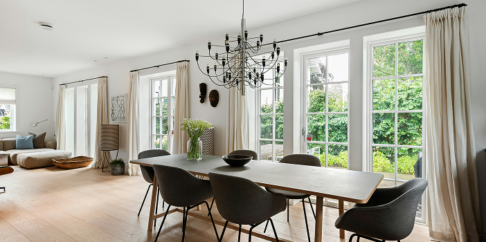 Light oak plank flooring in a dining room with a wood table, gray chairs, and black chandelier