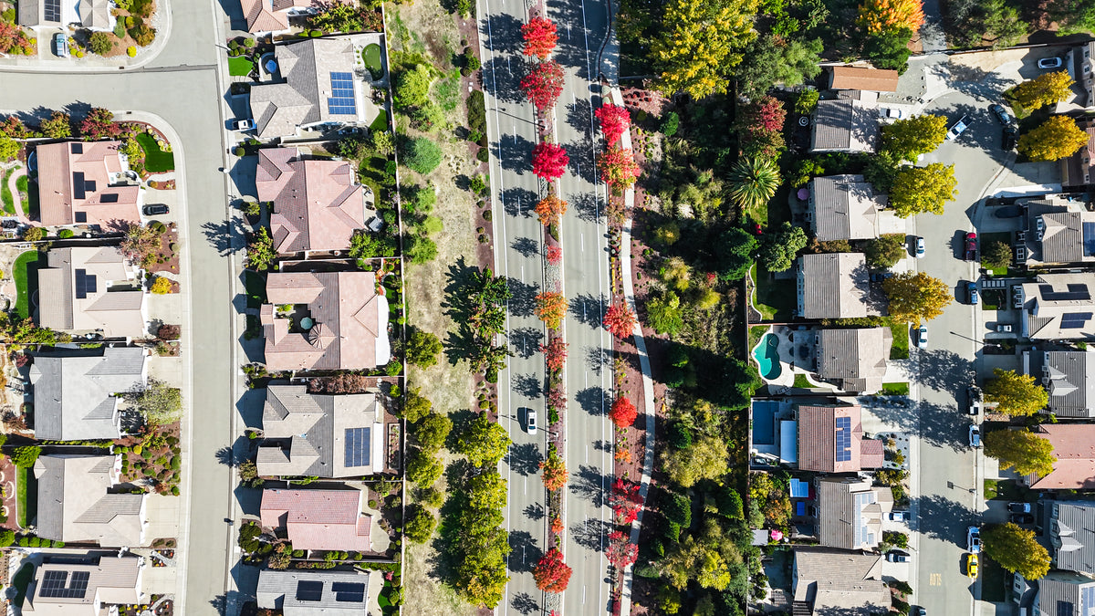 Aerial view of a Florin, suburban neighborhood with single-family homes, paved streets, and rows of trees showing green and red autumn foliage.