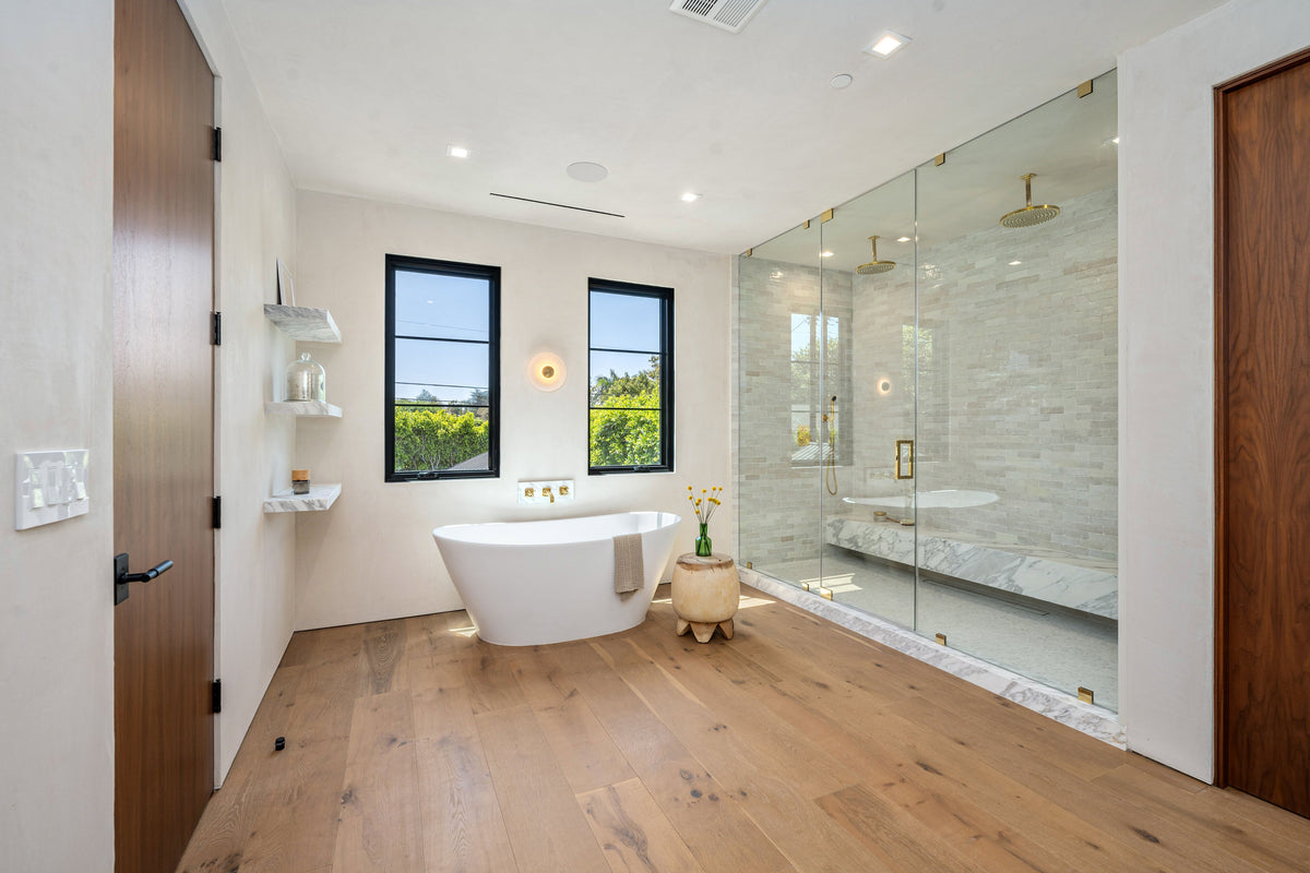 Light oak plank flooring in a modern bathroom with a freestanding tub and glass walk-in shower