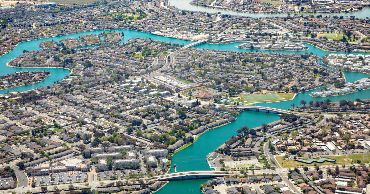 Aerial view Newark, California, with turquoise water channels, bridges, residential neighborhoods, and green parks.