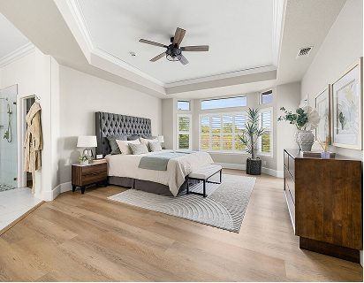 Light wood plank flooring in a bright modern bedroom with a dark tufted bed and gray patterned rug.