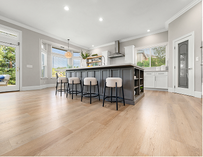 Light oak hardwood flooring in a bright modern kitchen with a gray island and four bar stools.
