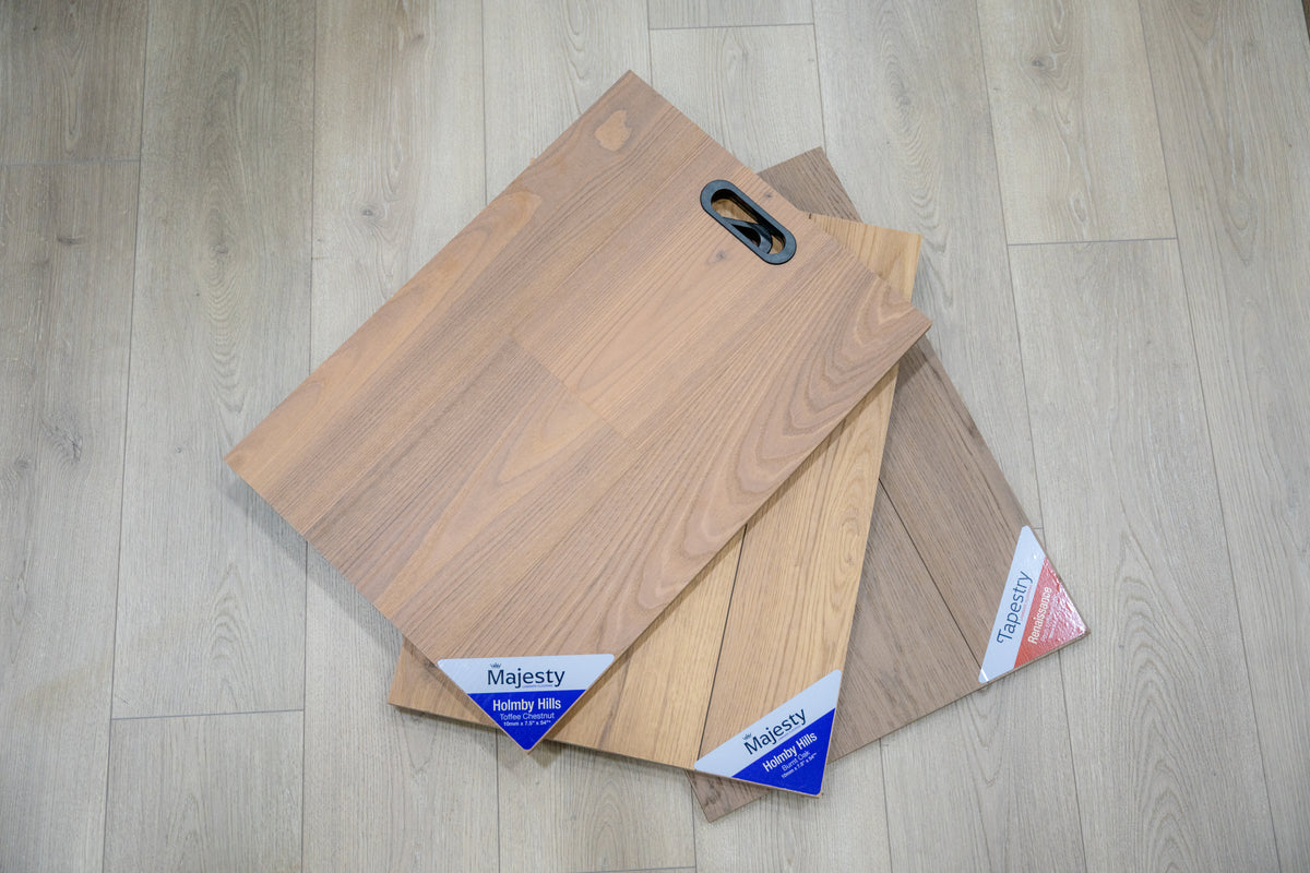 Majesty Holmby Hills wood flooring sample boards in light to medium brown tones, fanned out on gray plank flooring