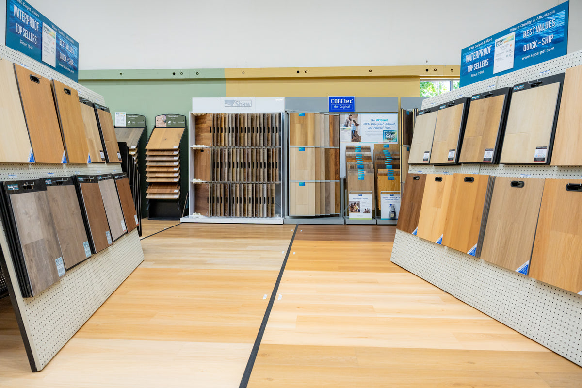 Showroom aisle lined with waterproof plank and hardwood sample boards at S&G Carpet