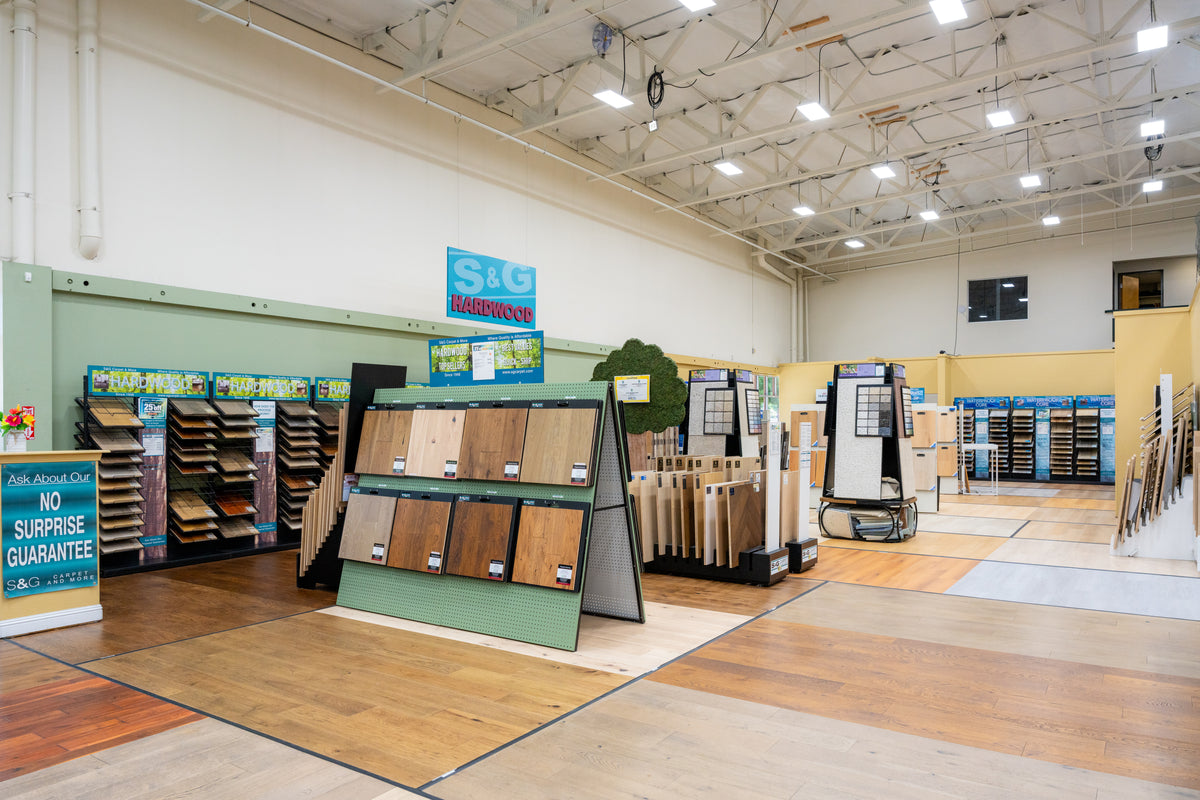 Hardwood section of the S&G Carpet showroom with plank sample displays and installed wood floors underfoot
