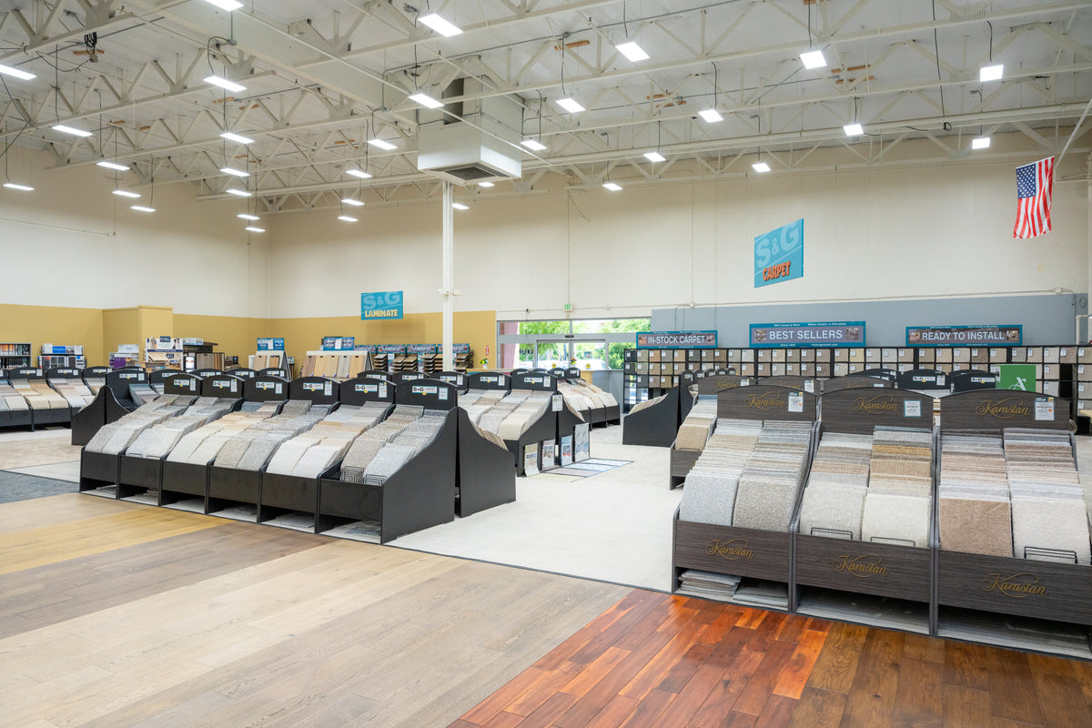 Interior of the S&G Carpet showroom with rows of carpet sample racks and hardwood flooring displays