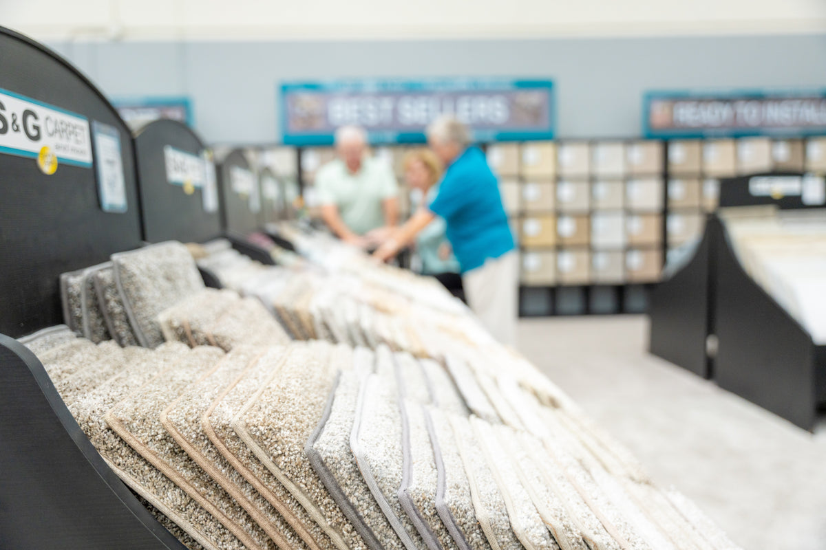 Rack of neutral carpet samples in the S&G Carpet showroom as customers browse in the background