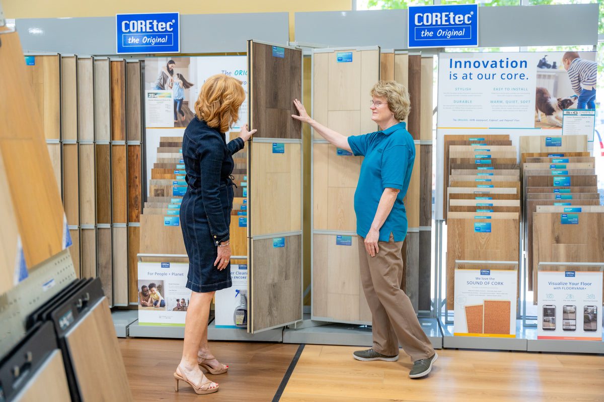 Customers browsing COREtec wood-look flooring samples on a showroom display rack