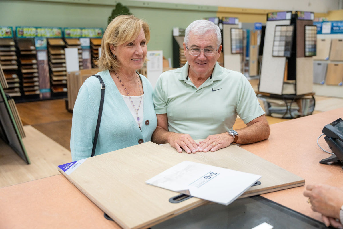 Couple at the counter with a wood flooring sample board in the S&G Carpet showroom