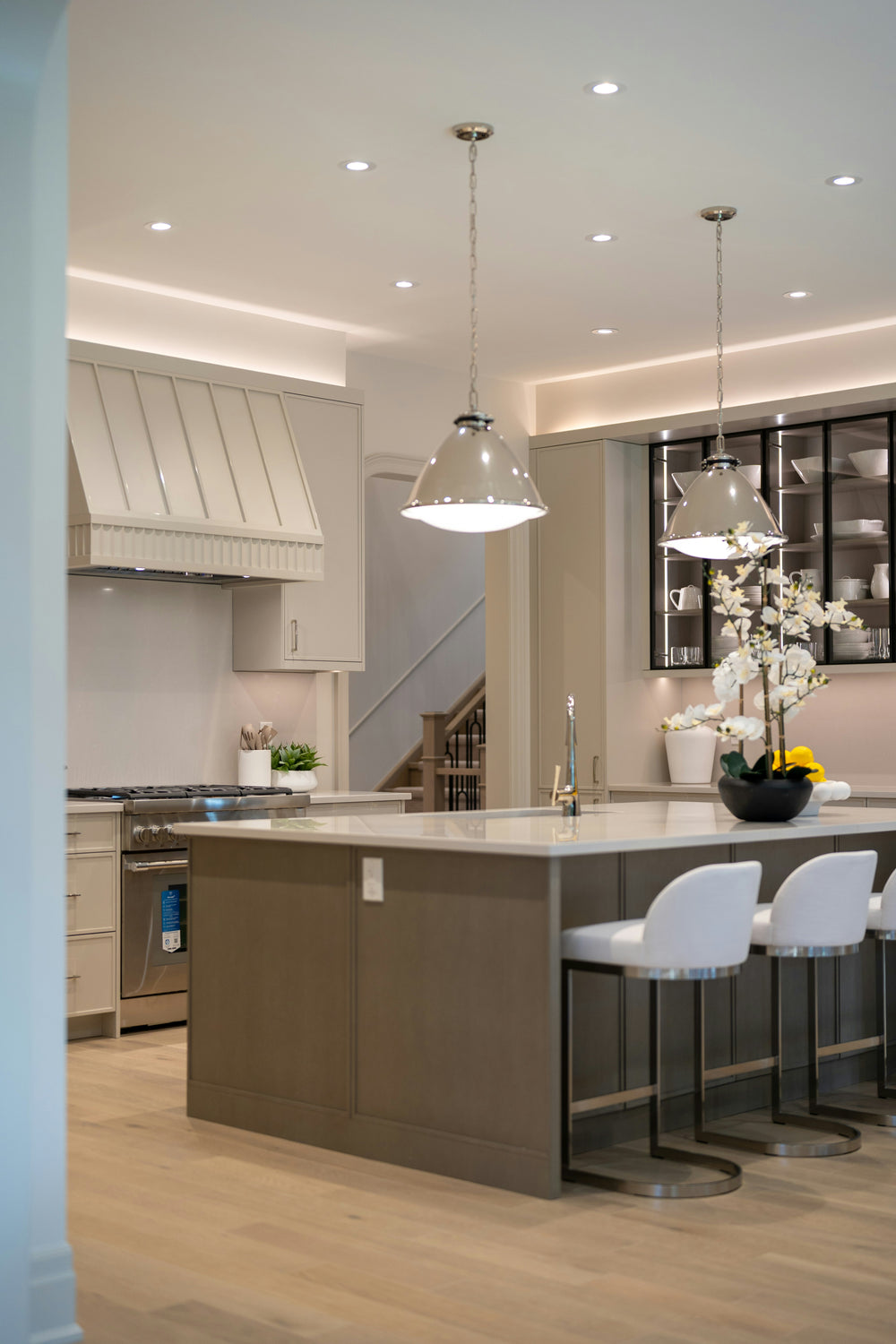 Light oak plank flooring in a modern kitchen with a gray island, bar stools, and pendant lights