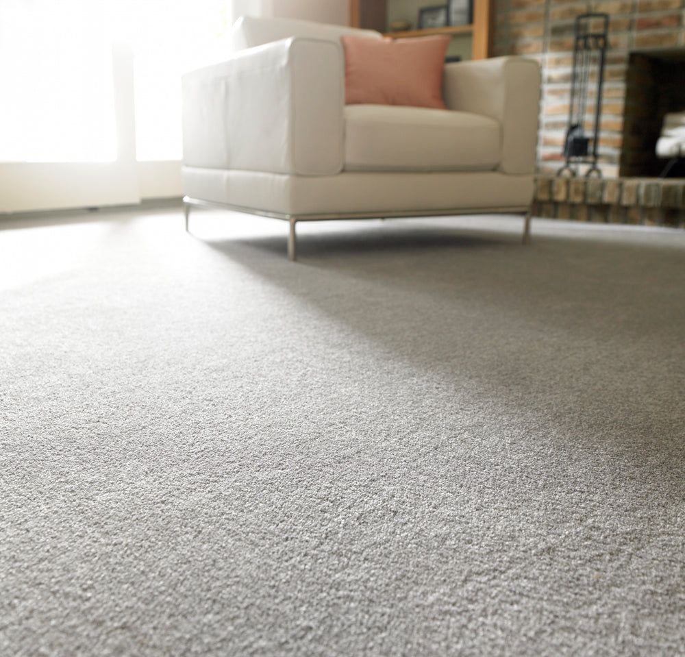 Gray cut-pile carpet in a living room with a white sofa and brick fireplace