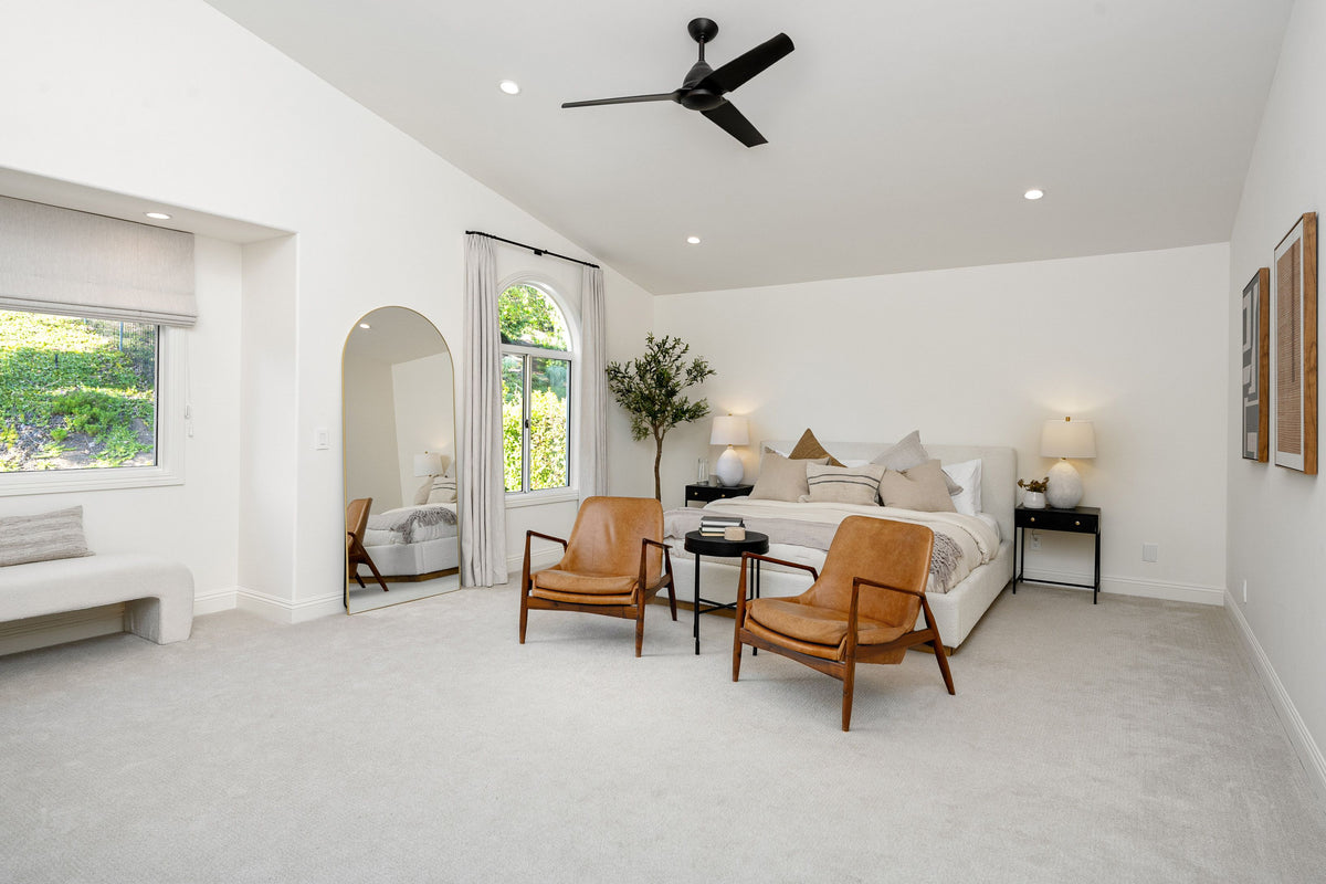 Soft light gray carpet in a bright bedroom with a upholstered bed and tan leather armchairs