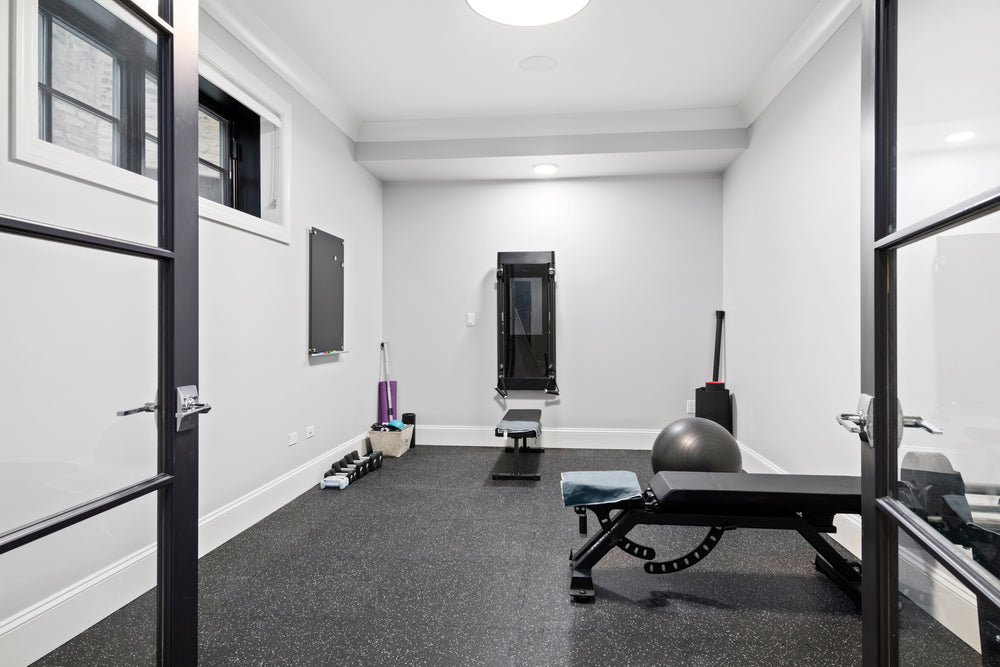 Speckled black rubber flooring in a home gym with a weight bench and exercise ball