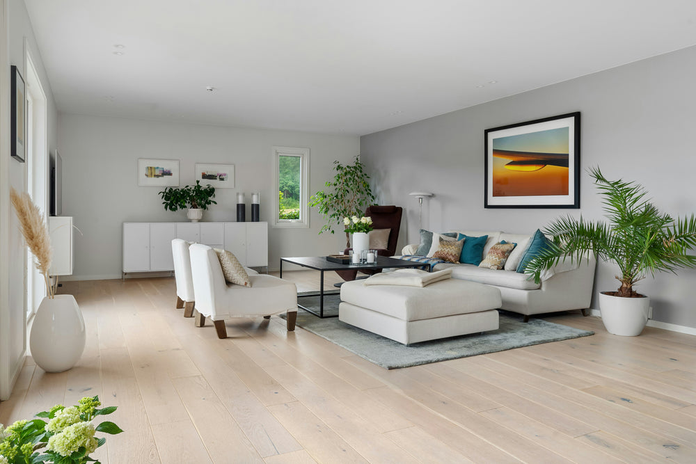 Wide-plank light oak flooring in a living room with a beige sectional, armchairs, and gray rug