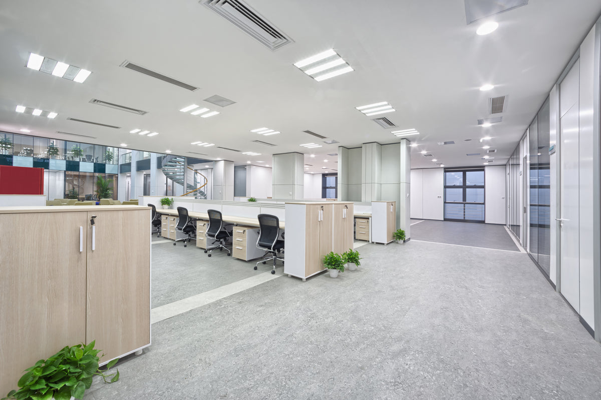 Gray commercial flooring in an open-plan office with workstations and glass partitions
