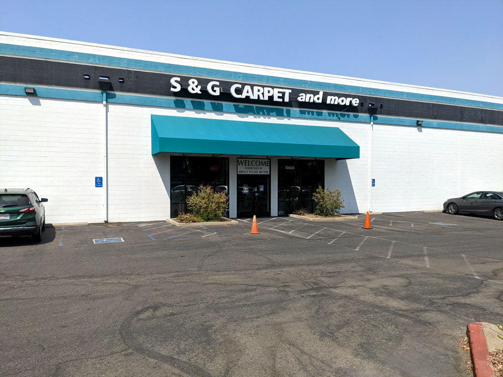 Exterior of the S&G Carpet and More flooring store in Rancho Cordova with a teal awning and parking lot