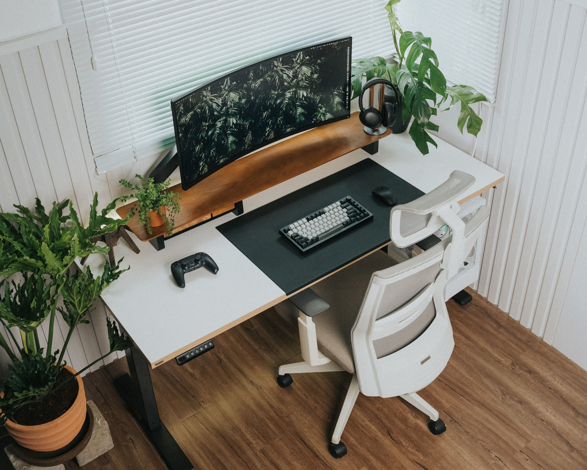 Medium brown wood-look plank flooring in a home office with a white desk, rolling chair, and potted plants