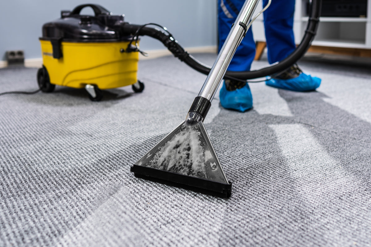 Professional carpet cleaning wand extracting foam from gray loop-pile carpet