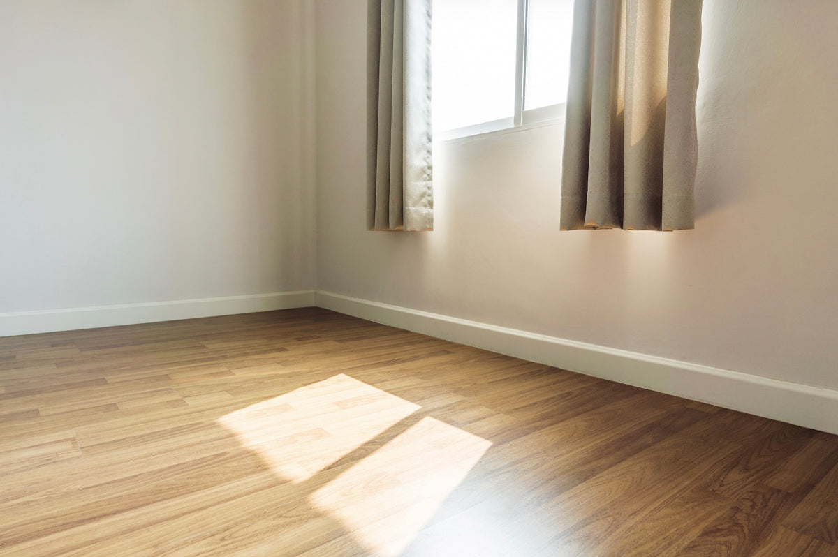 Warm brown wood-look vinyl plank flooring in a sunlit empty room with beige walls